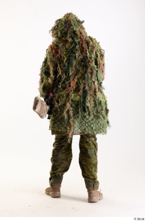 Andrew Elliott in Ghillie Pose with Gun holding gun standing…